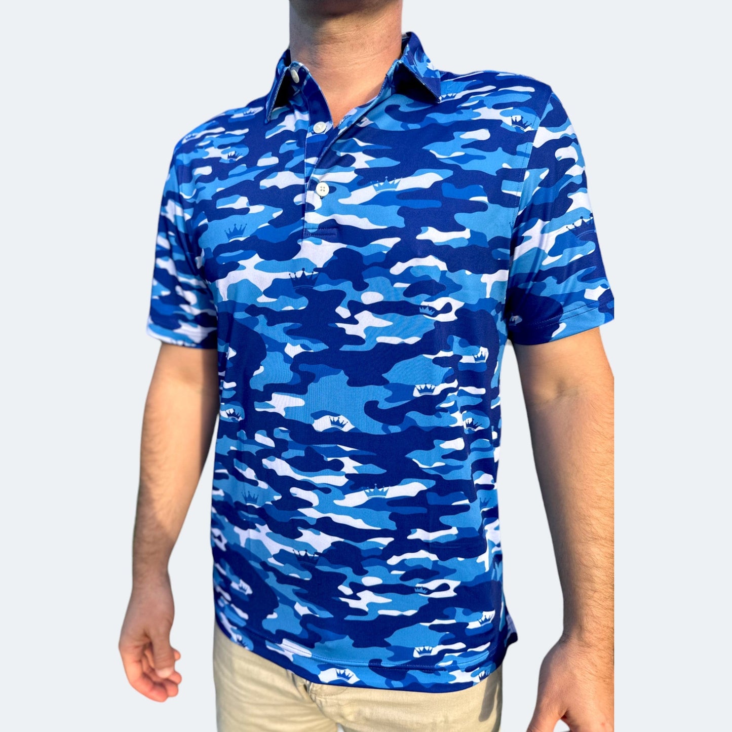 A person wearing a blue camouflage pattern golf polo with the VANSAINT crown logo on the chest.